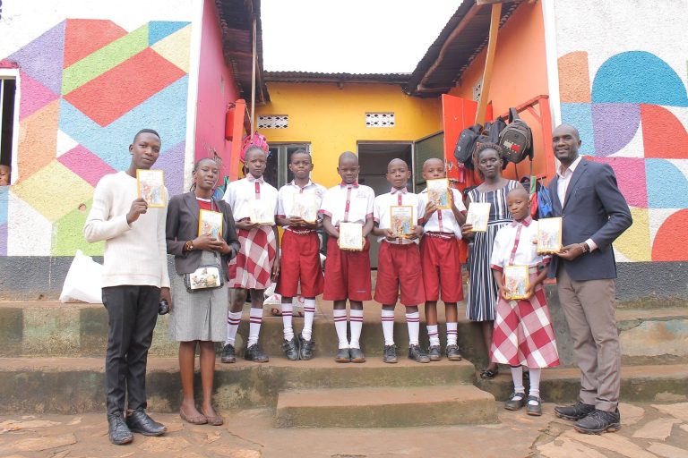 Students and teachers in Uganda holding their new Bibles outside a colourful school